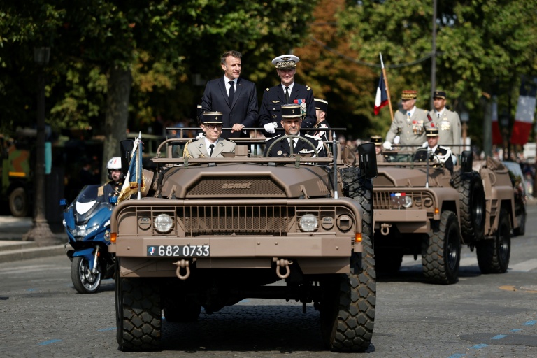 Le président Emmanuel Macron (c) à bord du véhicule de commandement aux côtés du chef d'état-major des armées Fabien Mandon (c,d) lors du défilé militaire annuel sur l'avenue des Champs-Élysées à Paris, le 14 juillet 2026