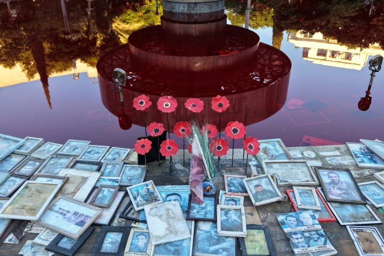 Des portraits de victimes israéliennes disposés autour de la fontaine Dizengoff, teintée de colorant rouge pour marquer le troisième anniversaire de l'attaque du 7-Octobre, à Tel-Aviv, le 7 octobre 2026