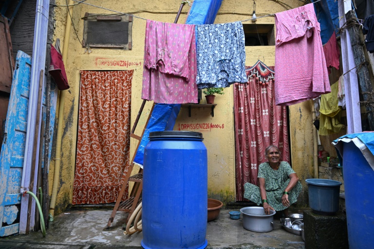 Une habitante, éligible à la relocalisation dans le cadre d'un projet de rénovation urbaine, lave des ustensiles devant son logement du bidonville de Dharavi, le 9 juillet 2025 à Bombay, en Inde