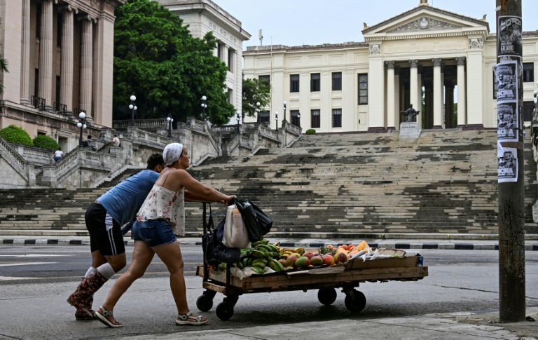 Un couple pousse un chariot avec de la nourriture devant l'Université de La Havane, à Cuba, le 4 juin 2025