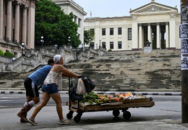 Un couple pousse un chariot avec de la nourriture devant l'Université de La Havane, à Cuba, le 4 juin 2025