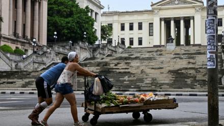 Un couple pousse un chariot avec de la nourriture devant l'Université de La Havane, à Cuba, le 4 juin 2025
