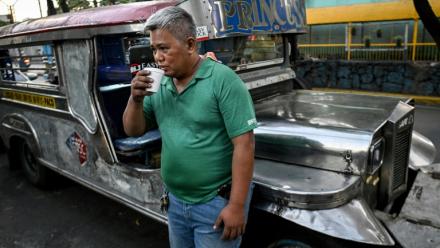 Le chauffeur de jeepney Eric Helera boit un café pendant une pause avant de prendre la route à Manille, le 23 mars 2026