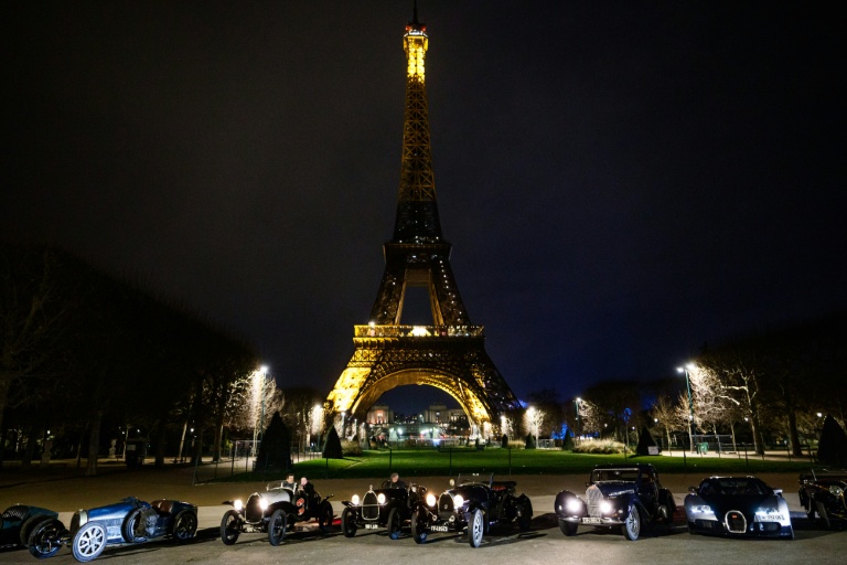 Des voitures de collection Bugatti sur le champ de Mars, devant la tour Eiffel, durant la parade nocturne pour les 50 ans de Rétromobile, le 26 janvier 2026, à Paris