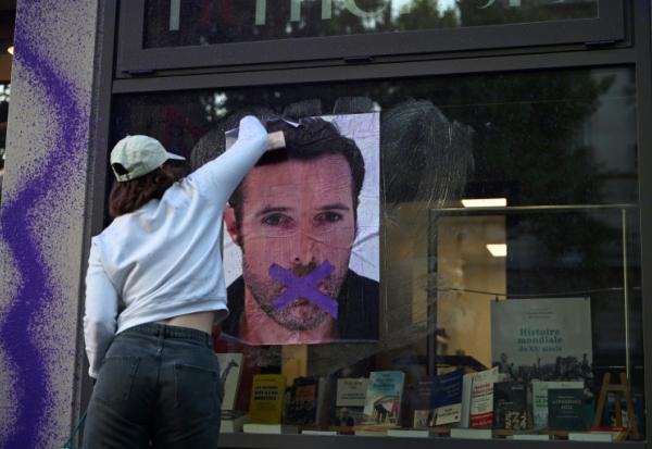 Une militante féministe colle une affiche dénonçant la publication d'un livre de Nicolas Bedos, condamné en octobre pour agressions sexuelles, le 23 mai 2025 à Paris