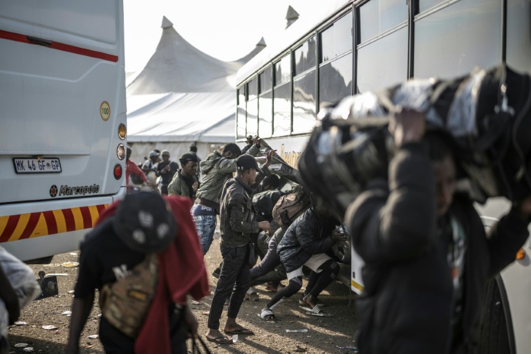 Des migrants sans papiers s'apprêtent à monter dans un bus pour être transférés vers la frontière avec le Zimbabwe, le 29 juin 2026 à Durban, en Afrique du Sud
