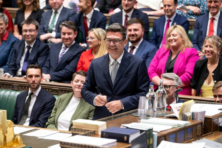 Photo diffusée par le Parlement britannique du nouveau député travailliste de Makerfield, Andy Burnham (c), souriant, après avoir signé le registre à la suite de sa prestation de serment à la Chambre des communes, le 22 mai 2026 à Londres 