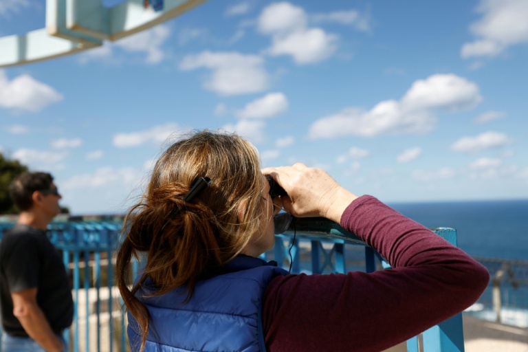 Des Israéliens regardent en direction de la mer Méditerranée, dans l'attente de l'arrivée du porte-avions américain Gerald Ford, à Haïfa dans le nord d'Israël, le 27 février 2026