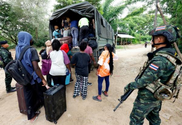 Des personnes de différentes nationalités qui travaillaient dans le complexe KK Park en Birmanie et ont traversé la frontière thaïlandaise par une rivière, montent à bord d'un véhicule sous la surveillance de soldats thaïlandais dans le district de Mae Sot, dans la province thaïlandaise de Tak, le 24 octobre 2025
