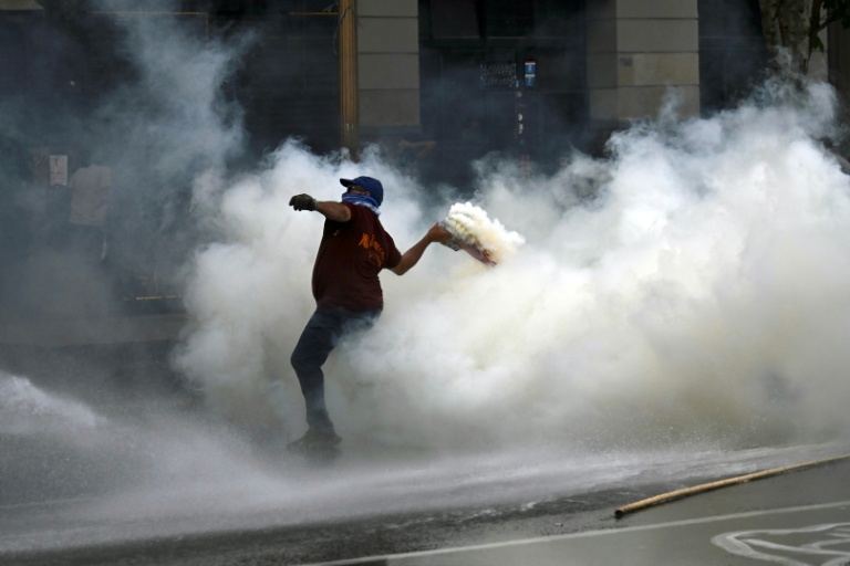 Un manifestant renvoie une grenade lacrymogène tirée par la police lors d'une manifestation devant le bâtiment du Parlement, où la réforme du travail du président argentin Javier Milei est examinée, à Buenos Aires, le 19 février 2026