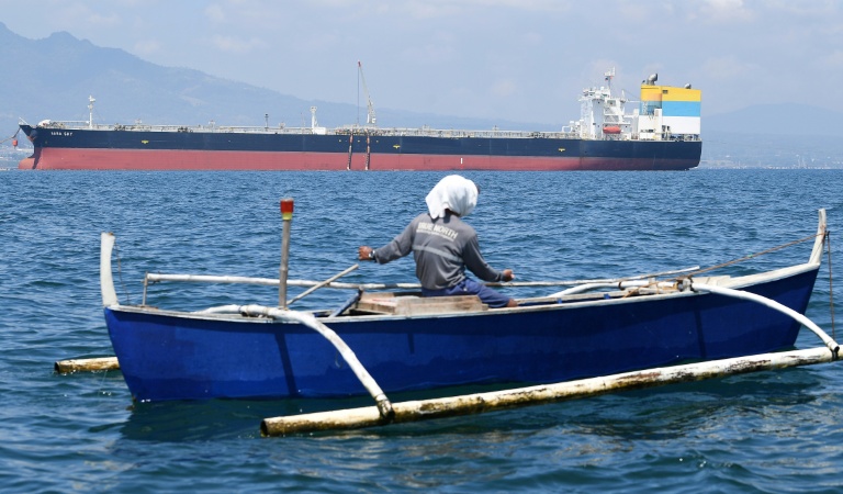 Un pêcheur passe à proximité du navire Sara Sky, battant pavillon sierra-léonais et transportant du pétrole brut russe, à l'ancrage au port de Limay, dans la province de Bataan, le 26 mars 2026 aux Philippines