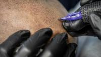 Remy, tatoueur professionnel, réalise une intervention de micropigmentation du cuir chevelu sur un client, dans son studio de Ginowan, à Okinawa au Japon, le 19 mai 2026