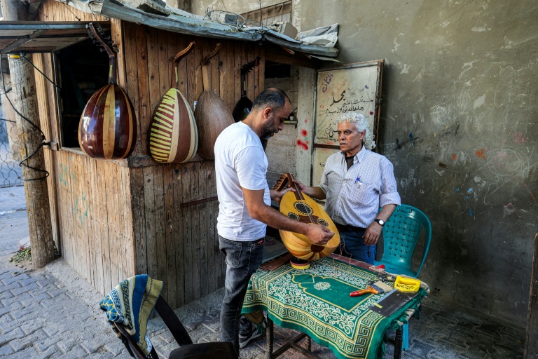 Le luthier palestinien Souhail Abou Chawich reçoit un ouds à réparer dans son atelier du camp de réfugiés de Nousseirat, dans le centre de la bande de Gaza, le 23 juin 2026