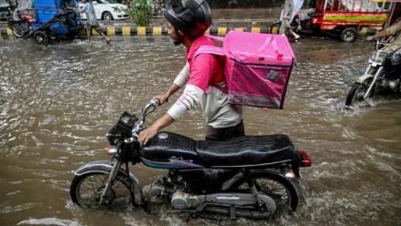 Abdullah Abbas, livreur de repas, pousse sa moto dans une rue inondée après de fortes pluies à Lahore, le 30 août 2025 au Pakistan