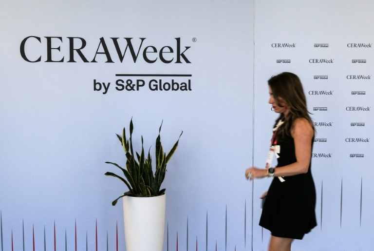 Une femme passe devant un panneau de la CERAWeek, plus grand rassemblement annuel des acteurs du pétrole, le 22 mars 2026 à Houston, au Texas