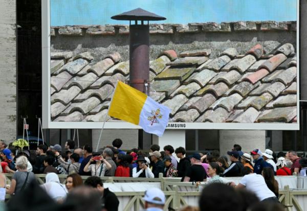 Des fidèles à Rome scrutent sur un écran la cheminée de la chapelle Sixtine au deuxième jour du conclave le 8 mai 2025