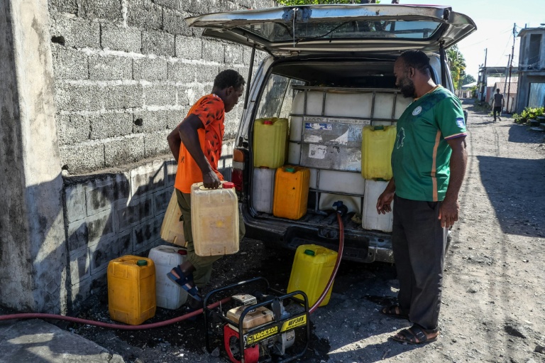 des habitants repartent avec des bidons remplis d'eau potable à la pompe du quartier, à Moroni, aux Comores, le 18 juillet 2026