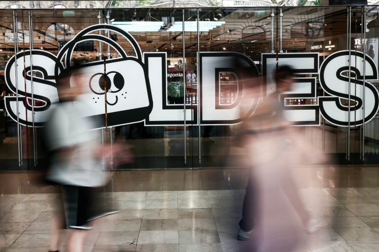 Des passants marchent à proximité de l'entrée d'un centre commercial annonçant les soldes, le 25 juin 2025 à Paris