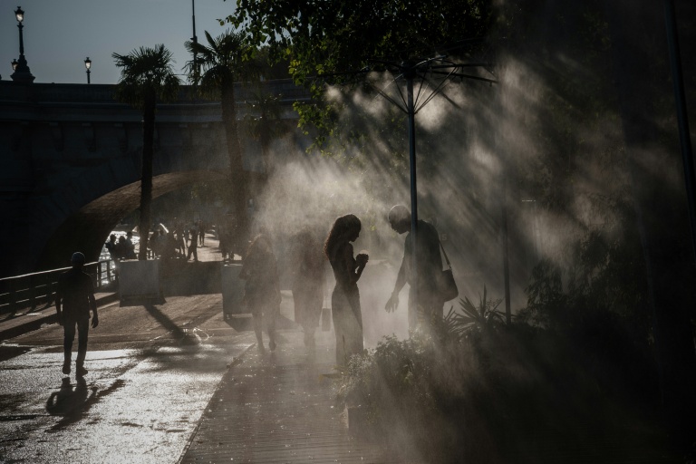 Des personnes se rafraîchissent sous des brumisateurs à Paris, le 10 juillet 2026
