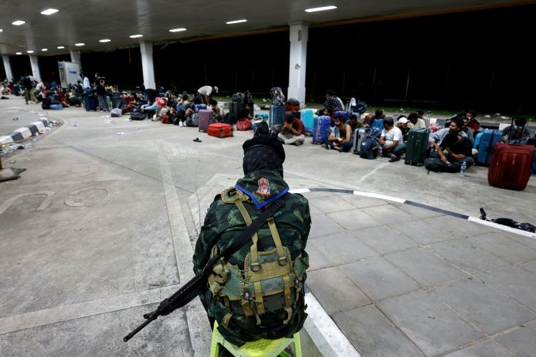 Un soldat thaïlandais surveille des personnes qui ont traversé la frontière depuis la Birmanie, en attente d'être contrôlées et interrogées par les autorités  dans le district de Mae Sot, dans la province de Tak, le 23 octobre 2025