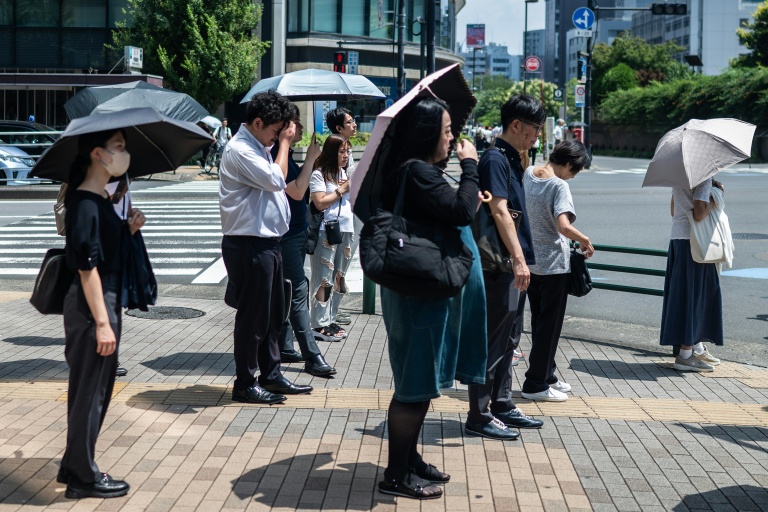 Les gens portent des parapluies pour se protéger du soleil à Tokyo le 23 juillet 2026