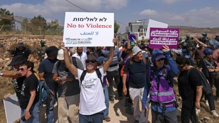 Des militants israéliens et des bénévoles solidaires rassemblés devant une maison palestinienne assiégée par des colons israéliens dans le village de Qusra, au sud de Naplouse, en Cisjordanie occupée, le 14 août 2026