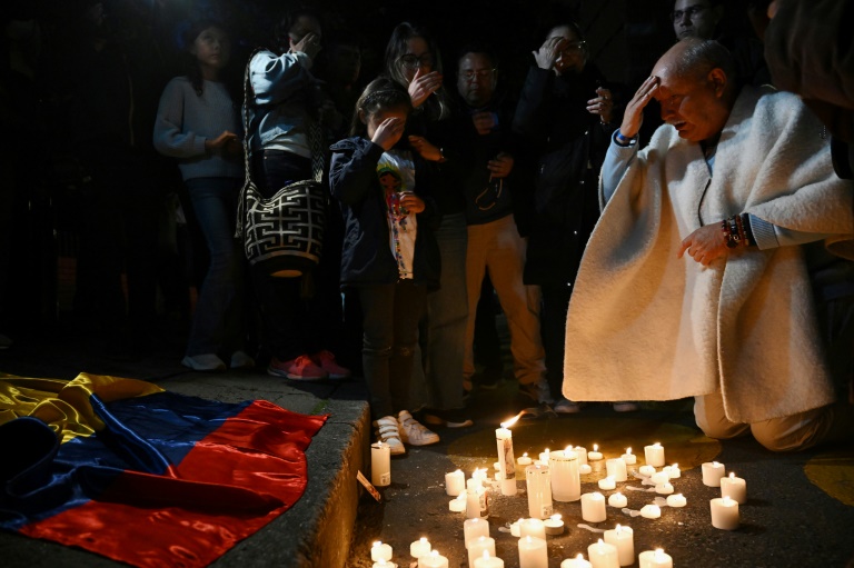 Des personnes prient après avoir allumé des bougies devant la clinique Sante Fe où le sénateur conservateur Miguel Uribe reçoit des soins médicaux après avoir été blessé par balle lors d'un meeting à Bogota, le 7 juin 2025