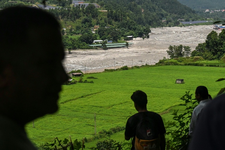 Des habitants regardent la rivière Trishuli alors qu’ils se réfugient sur un terrain surélevé après une alerte aux inondations dans la région de Pipaltar, dans le district de Nuwakot au Népal, le 28 août 2026