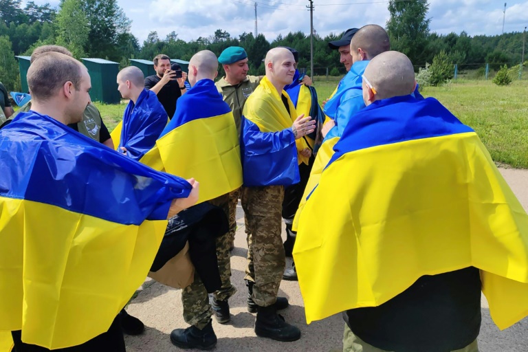 Photo prise et diffusée par le service de presse présidentiel ukrainien, le 9 juin 2025, de prisonniers de guerre ukrainiens enveloppés de drapeaux nationaux après un échange dans un lieu non divulgué
