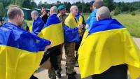 Photo prise et diffusée par le service de presse présidentiel ukrainien, le 9 juin 2025, de prisonniers de guerre ukrainiens enveloppés de drapeaux nationaux après un échange dans un lieu non divulgué
