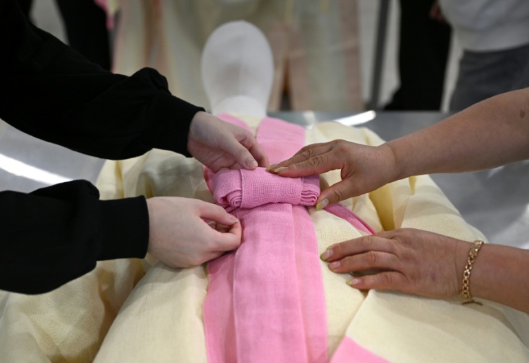 Des étudiants s'entraînent sur un mannequin à revêtir un défunt dans une salle de classe de l'Institut des sciences et technologies de Busan, dans le sud-est de la Corée du Sud, le 24 septembre 2025