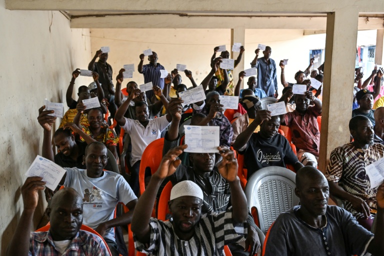 Des producteurs de cacao brandissent des reçus montrant qu'ils n'ont toujours pas été payés, lors d'une réunion avec les coopératives d'achat, à Songan, un village près d'Aboisso, dans le sud ivoirien, le 17 mars 2026