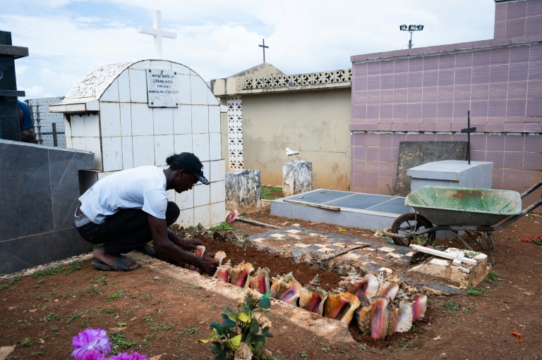 Un homme dispose des coquillages sur une tombe dans le cimetière de Sainte-Rose-de-Lima, à Sainte-Rose en Guadeloupe, le 31 octobre 2025