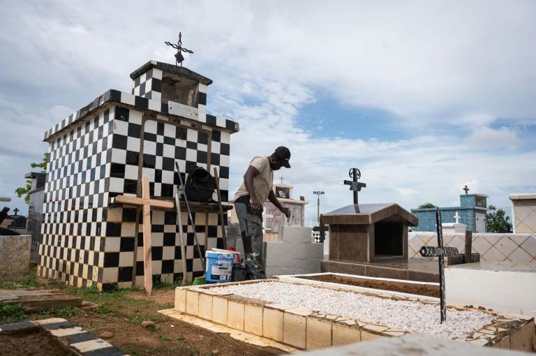 Un homme repeint une tombe dans le cimetière de Sainte-Rose-de-Lima, à Sainte-Rose en Guadeloupe, le 31 octobre 2025