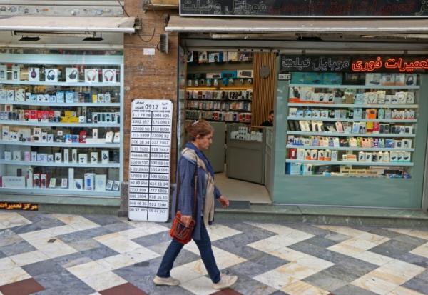 Une Iranienne passe devant une boutique de téléphonie mobile, le 19 avril 2026 à Téhéran
