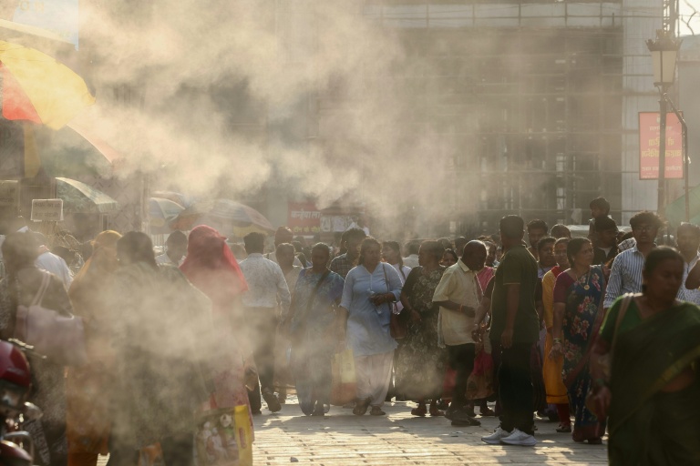 Des passants dans une rue rafraichie par des brumisateurs à Varanasi, en Inde, en pleine vague de chaleur le 15 mai 2026