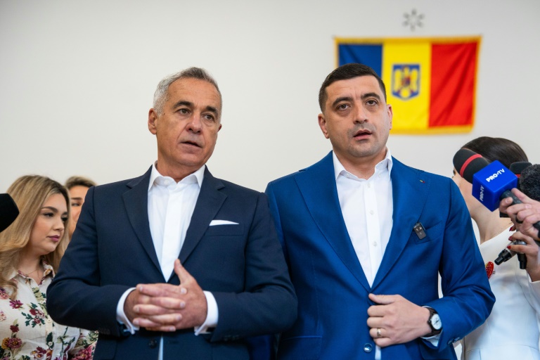 L'ex candidat d'extrême droite à la présidentielle roumaine Calin Georgescu et son successeur George Simion, le 18 mai 2025 dans un bureau de vote de Mogosoaia
