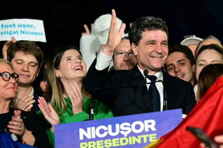 Le maire de Bucarest et candidat à la présidence roumaine, Nicusor Dan, salue ses partisans à l'annonce des sondages de sortie des urnes, le 18 mai 2025 à Bucarest