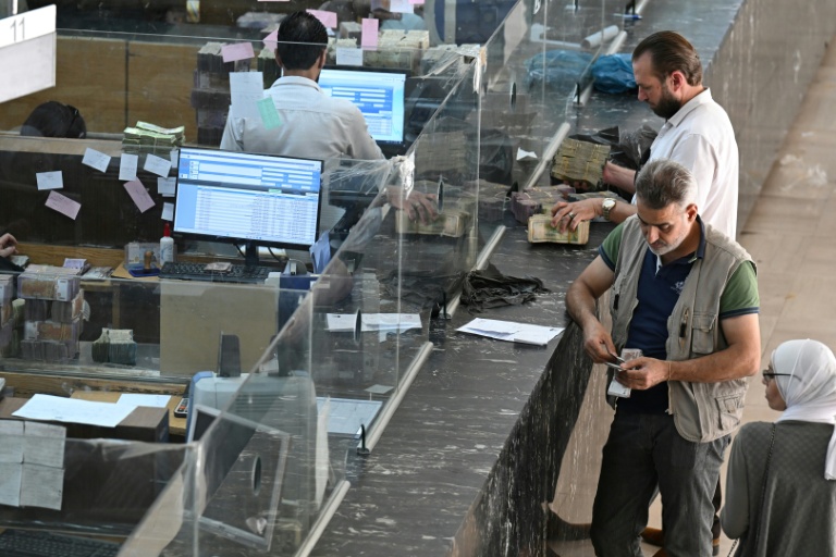 Des clients attendent aux guichets de la banque centrale de Damas, le 21 mai 2025 en Syrie