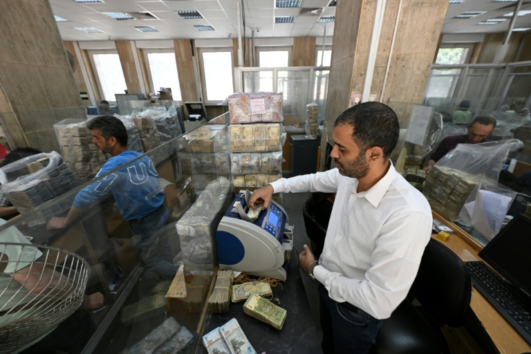 Des employés de la banque centrale de Damas comptent des piles de livres syriennes, le 21 mai 2025