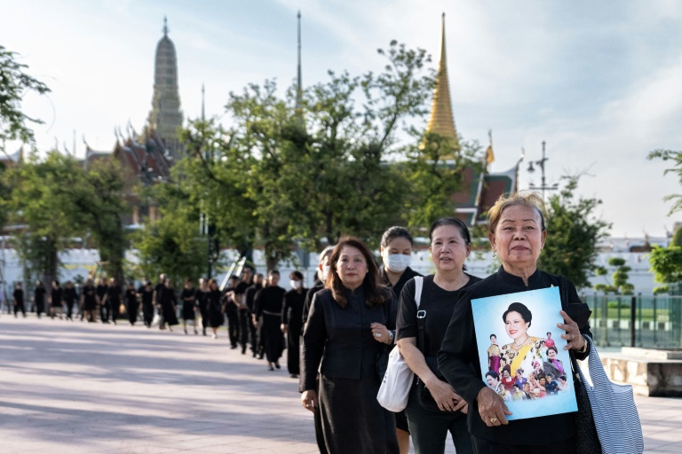 Des personnes en deuil tiennent des portraits de l'ancienne reine Sirikit de Thaïlande en faisant la queue pour rendre hommage à la défunte reine au Grand Palais de Bangkok, le 26 octobre 2025