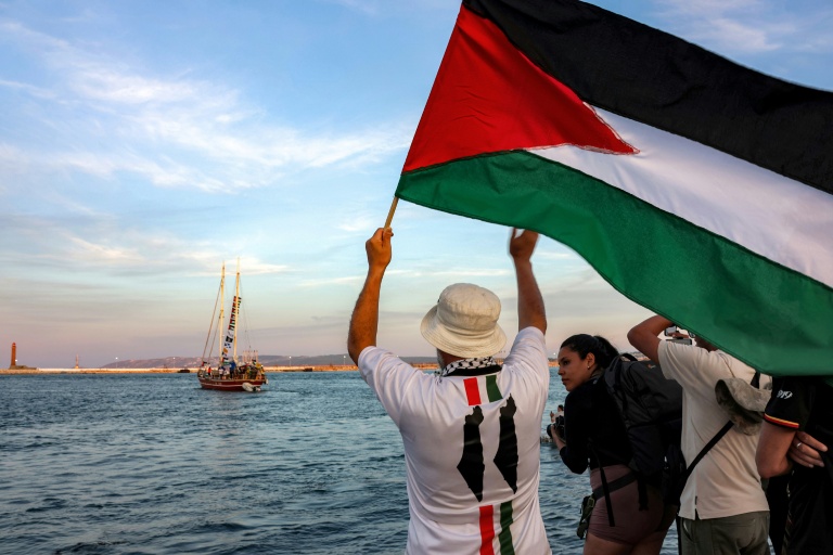 Un homme agite un drapeau palestinien à l'adresse d'activistes se trouvant dans un bateau quittant le port tunisien de Bizerte pour Gaza, le 14 septembre 2025