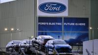 Des voitures du constructeur automobile américain Ford sont alignées sur un camion transporteur devant le logo de l'entreprise à l'usine Ford de Cologne, dans l'ouest de l'Allemagne, le 25 novembre 2024