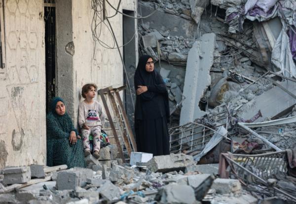 Des femmes et un enfant au milieu des décombres d'une maison détruite lors d'une frappe israélienne nocturne à Gaza, le 29 octobre 2025