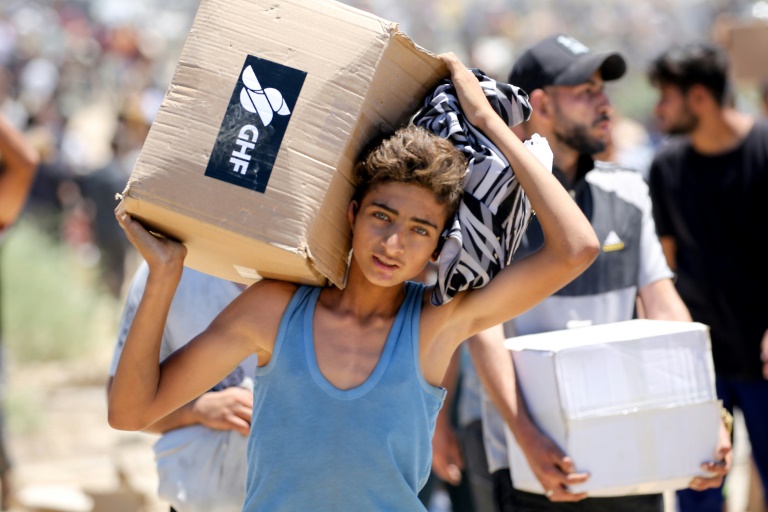 Un garçon porte une boîte d'aide humanitaire de la Fondation humanitaire de Gaza (GHF), venant d'un centre de distribution dans le centre de la bande de Gaza le 29 mai 2025
