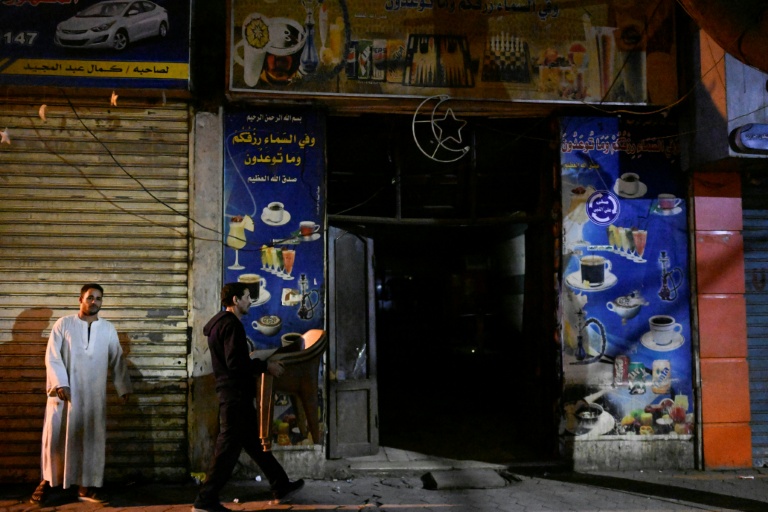 Un serveur enlève une table avant la fermeture d'un commerce en application du couvre-feu, dans le centre-ville du Caire, le 2 avril 2026 en Egypte