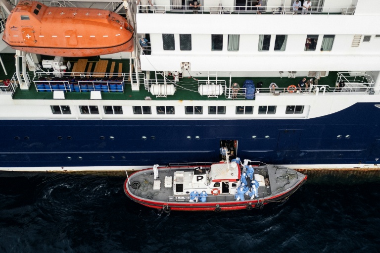 Vue aérienne de personnels de santé aidant des patients à monter à bord d’un bateau depuis le navire de croisière MV Hondius, au mouillage au large du port de Praia, le 6 mai 2026 au Cap-Vert