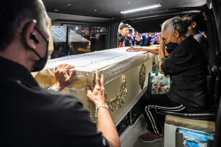 Une proche endeuillée accompagne le cercueil contenant la dépouille d'une victime de l'incendie d'un bar, dans un fourgon funéraire, le 14 juillet 2026 à l'hôpital général de la police de Bangkok, en Thaïlande