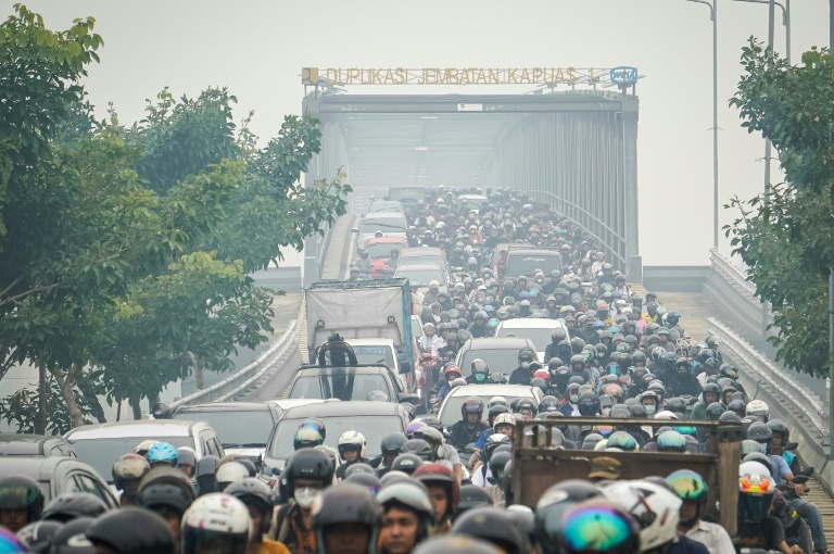 Des automobilistes et motocyclistes traversent une épaisse brume causée par des incendies de forêt et de terres sur le pont Duplikasi Jembatan Kapuas 1 à Pontianak, dans le Kalimantan occidental, le 7 octobre 2026 en Indonésie