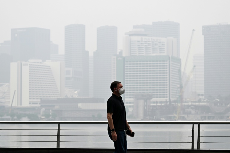 Un passant porte un masque de protection le long du boulevard à Marina Bay, noyé dans la brume, le 12 octobre 2026 à Singapour 
